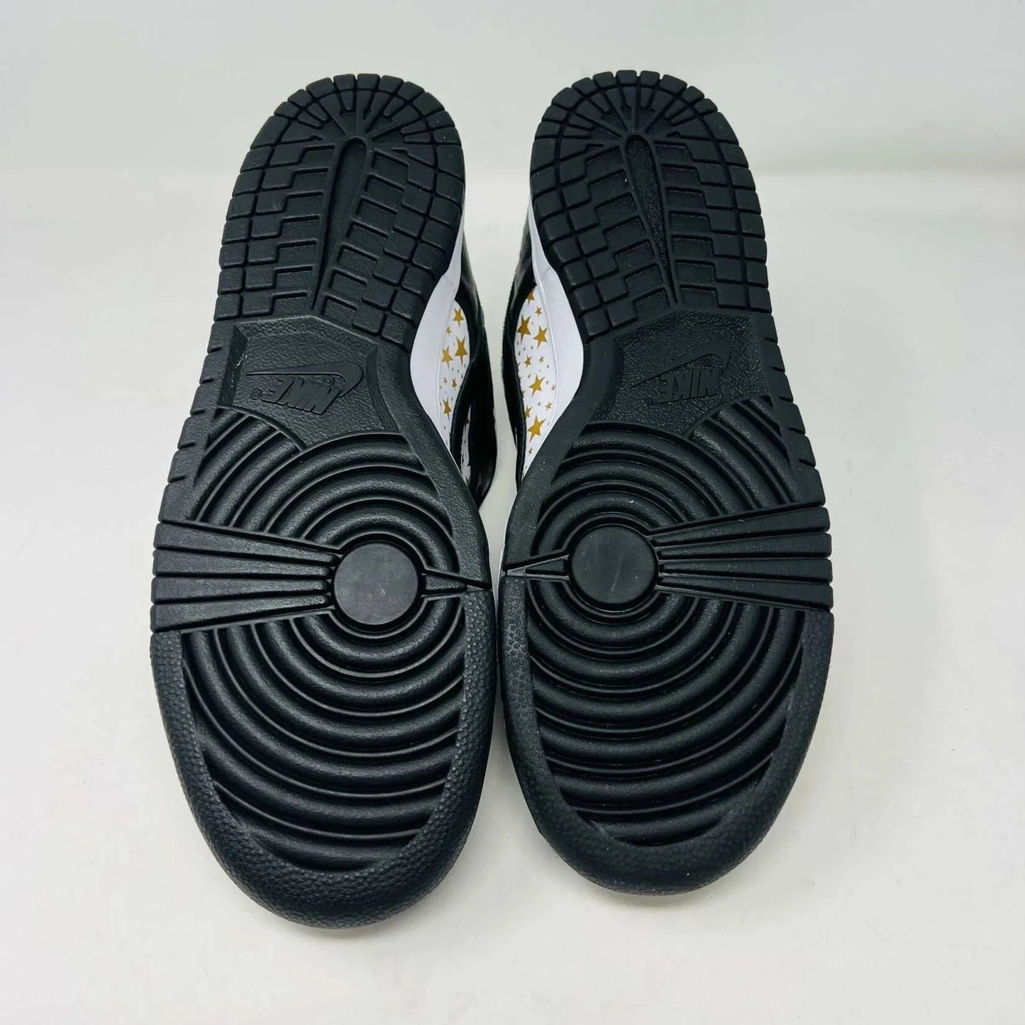 The authentic Nike SB Dunk Low Supreme Stars Black (2021) sneaker, featuring a gold star pattern and a WORLD FAMOUS Supreme tag, is presented in a purple Nike SB box with extra laces.