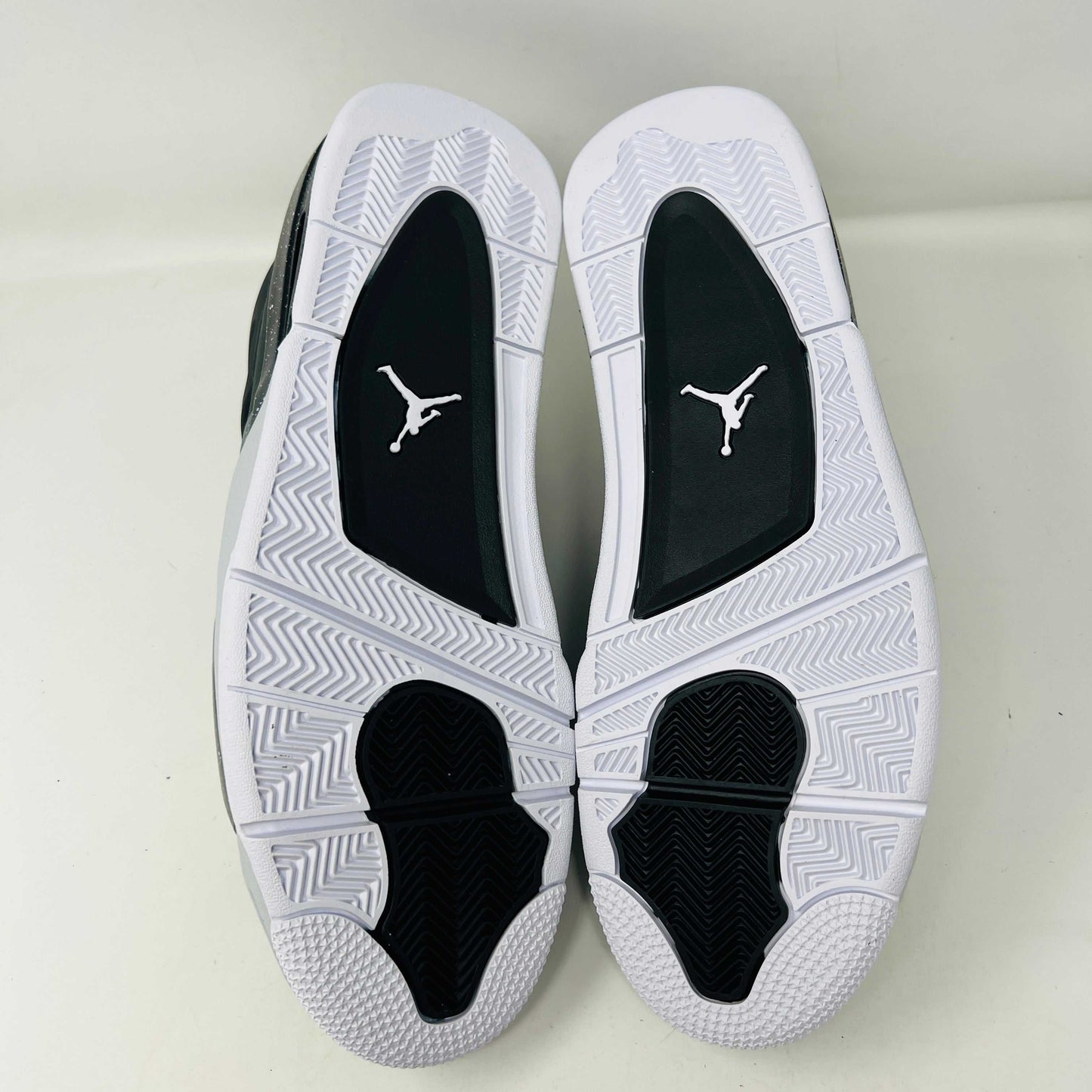 On top of a shoebox sits the brand-new Jordan 4 Retro Fear (2024), a stylish sneaker by Jordan. Its black and gray color scheme, black mesh accents, white midsole, and speckled heel details make it a must-have for 2024.