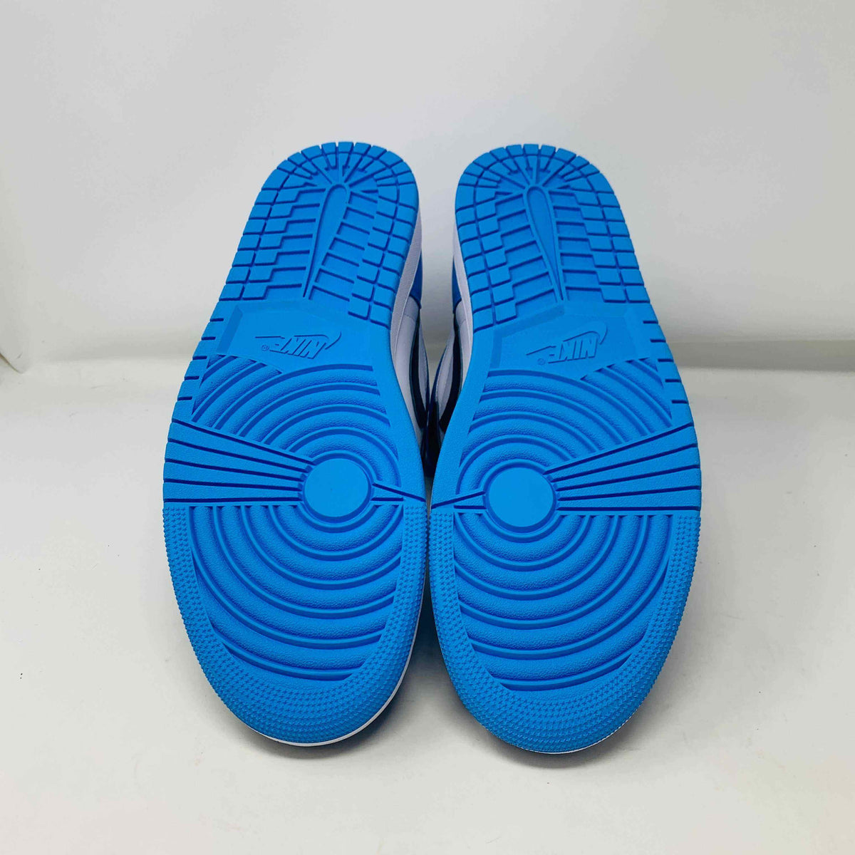Bottom view of Jordan 1 High UNC Toe sneakers with blue soles.