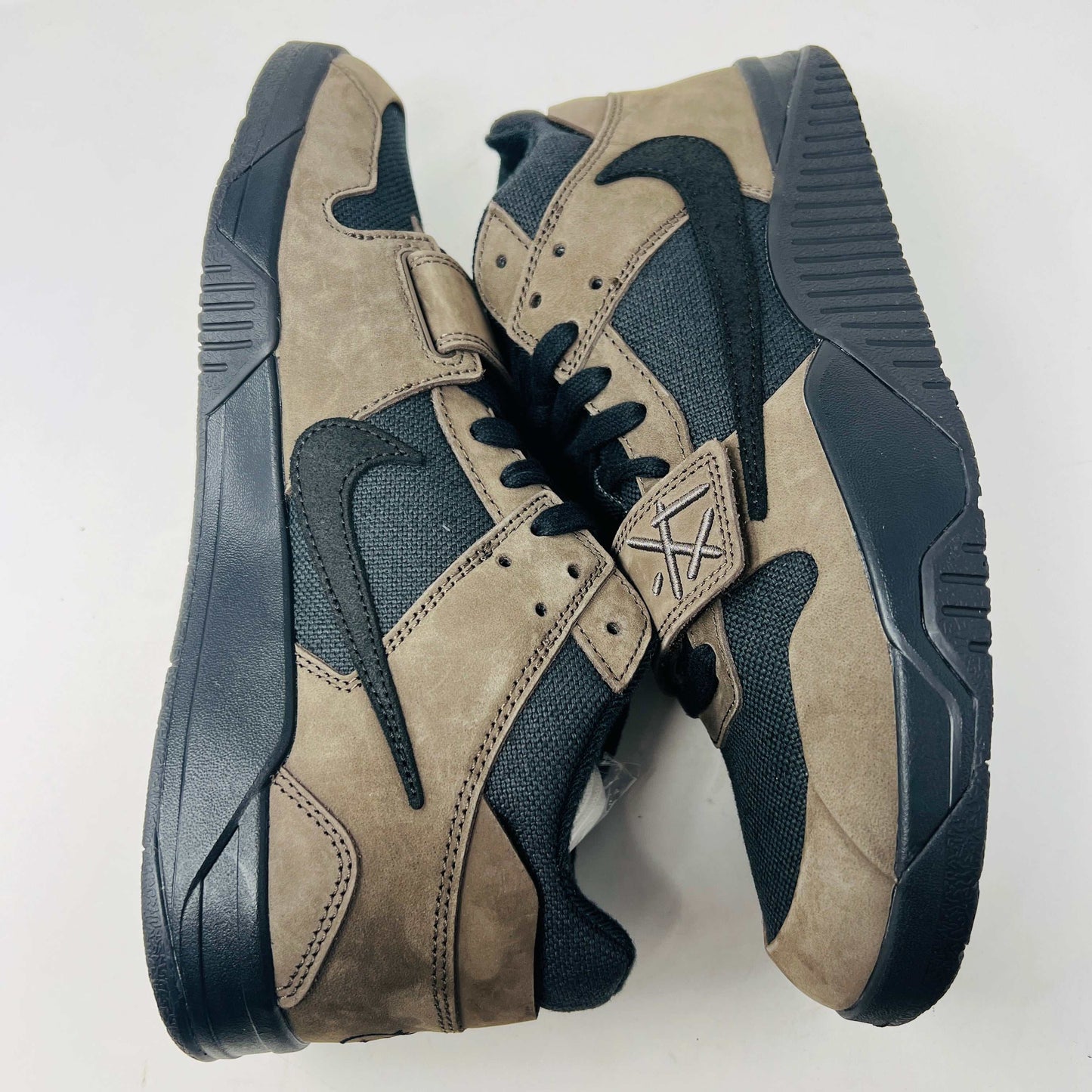 A pair of Jordan Jumpman Jack TR Travis Scott Dark Mocha sneakers are showcased on a brown box labeled JACK in white. The brown and black sneaker features a black swoosh, laces, and textured sole. Its 100% authentic with extra laces and bag, set against a plain white background.