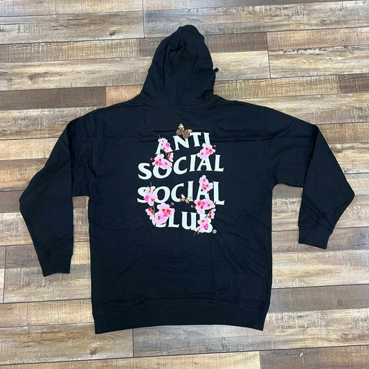 The Holy Ground Sneaker Shops BRAND NEW Anti Social Social Club Kkoch Hoodie in black (XXL) features the iconic text with pink floral designs on the back. Its 100% authentic, demonstrated by its craftsmanship and bold style, laid flat on a wooden floor.