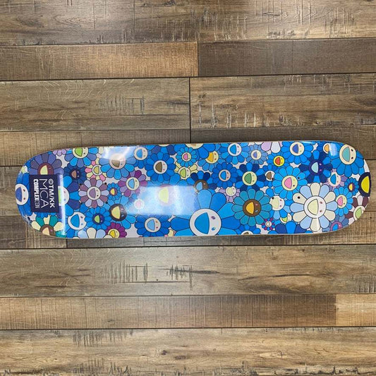 Takashi Murakami Flower Skateboard Deck Blue on wooden floor.