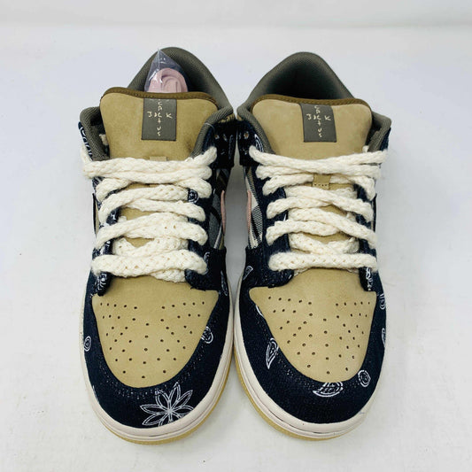 The Nike SB Dunk Low Travis Scott sneakers feature beige suede toe caps, black bandana-patterned overlays, white rope laces, authentic pink accents, and a brown label with text on the tongue. Brand new with extra laces, the interior is visible at the top.