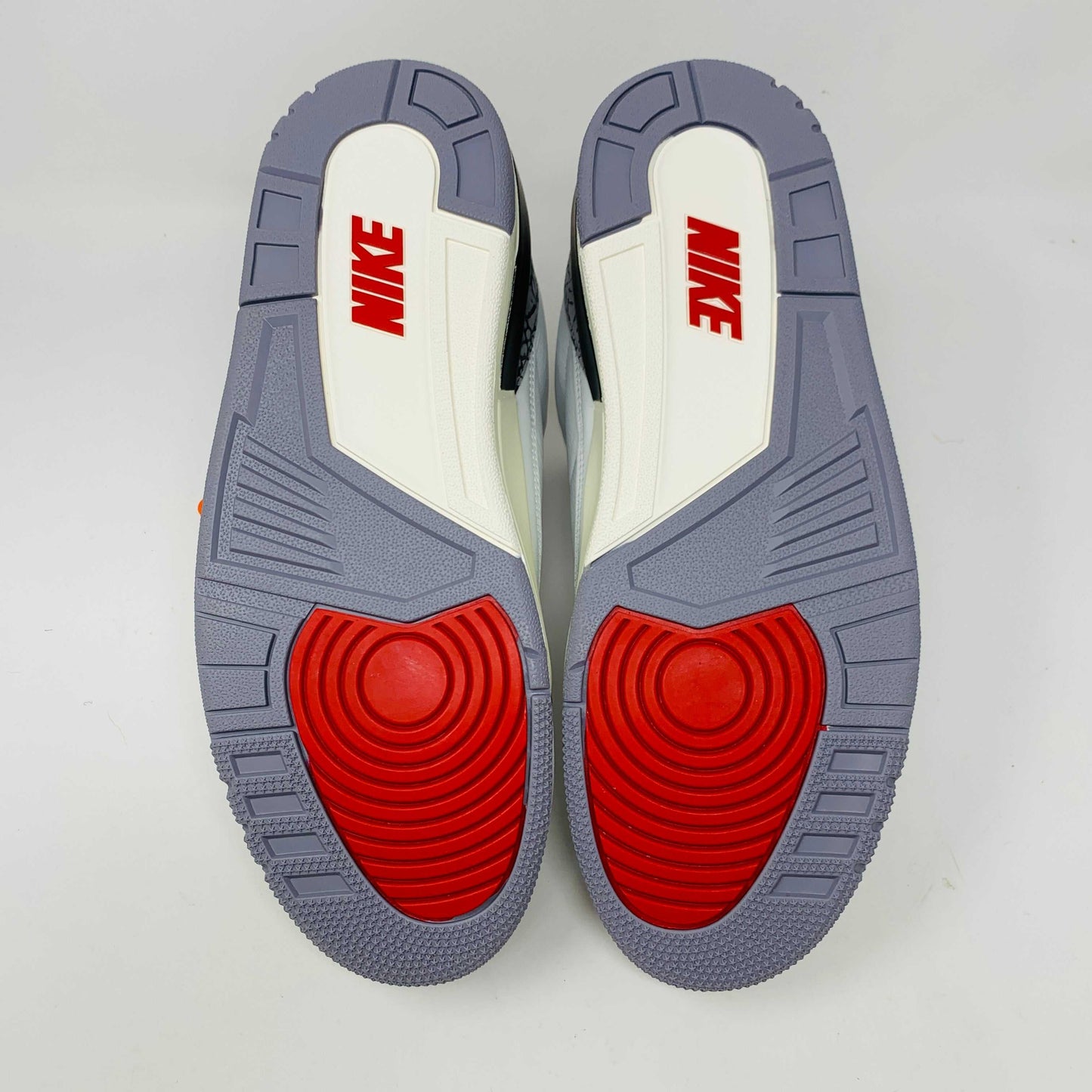 Jordan 3 Retro White Cement Reimagined sneakers with red, white, and gray outsoles.