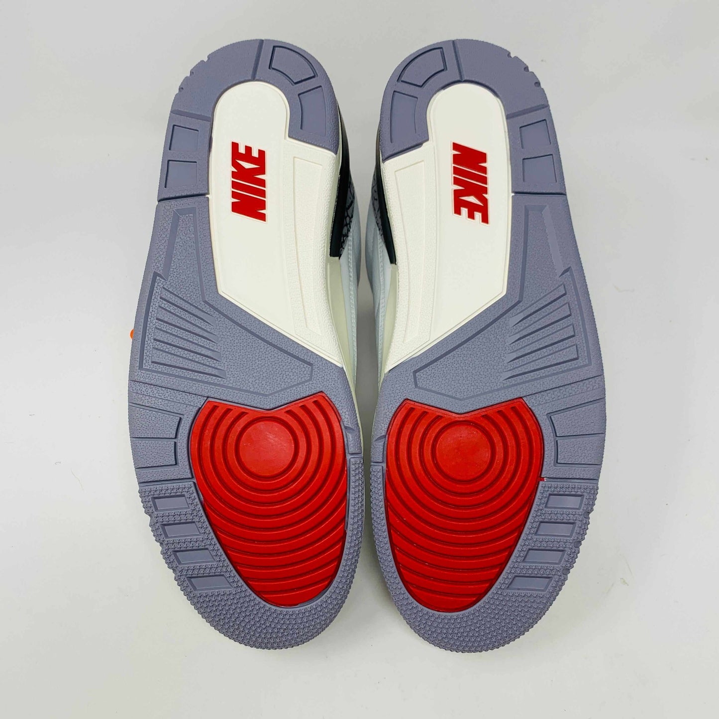 Jordan 3 Retro White Cement Reimagined sneakers with red, white, and gray outsoles.