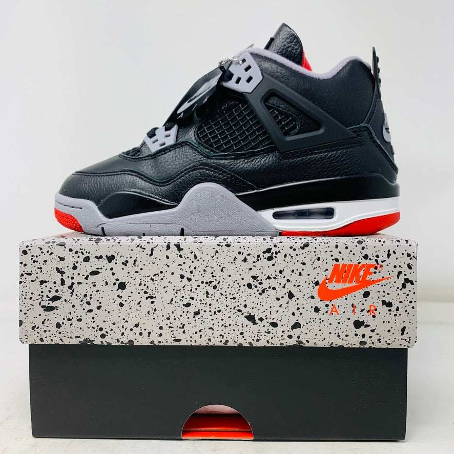 Jordan 4 Retro Bred Reimagined GS sneaker, black with red accents, on Nike Air box.