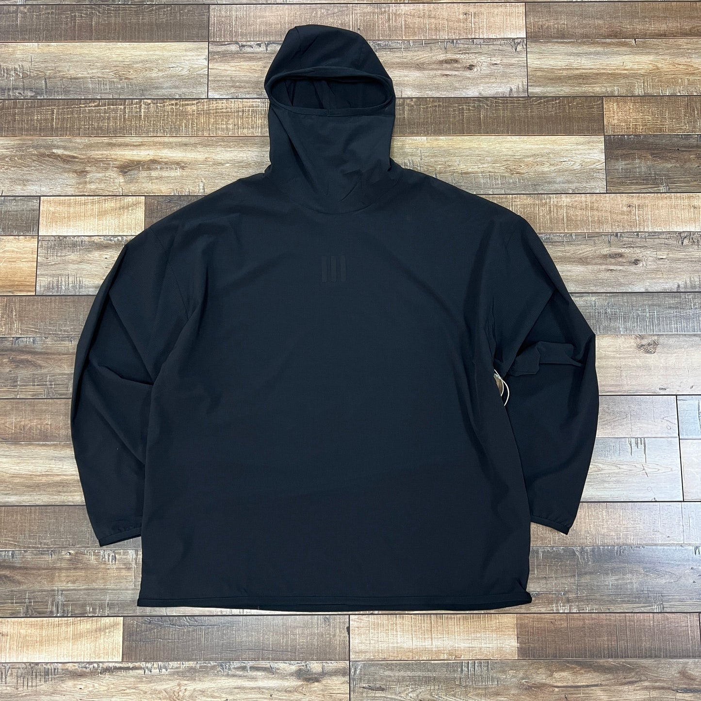 Fear of God Athletics Adidas black stretch woven running hoodie laid flat on wooden floor