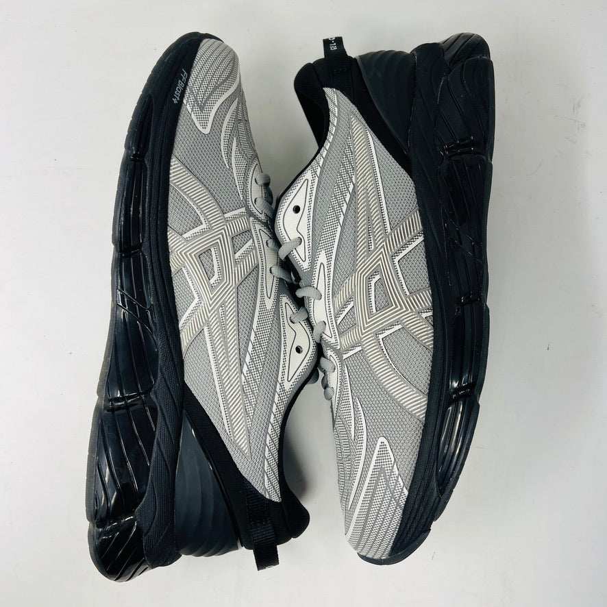 A side view of the ASICS Gel-Quantum 360 VIII C.P. Company in Cement Grey, featuring a sleek modern design with gray and silver elements, black accents, a black sole, and subtle patterns on its clean upper. The background is plain white.