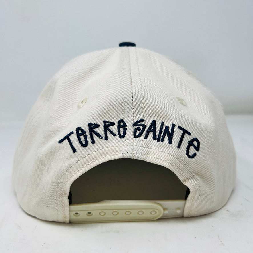 The Holy Ground Stussy Hat by Holy Ground is a streetwear accessory with HOLY GROUND embroidered in black on its white front panel, complemented by a green bill for a fresh touch.