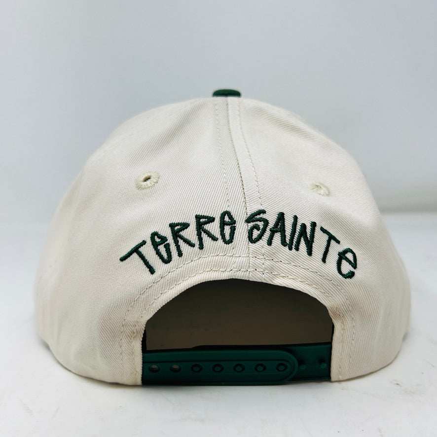 The Holy Ground Stussy Hat by Holy Ground is a streetwear accessory with HOLY GROUND embroidered in black on its white front panel, complemented by a green bill for a fresh touch.