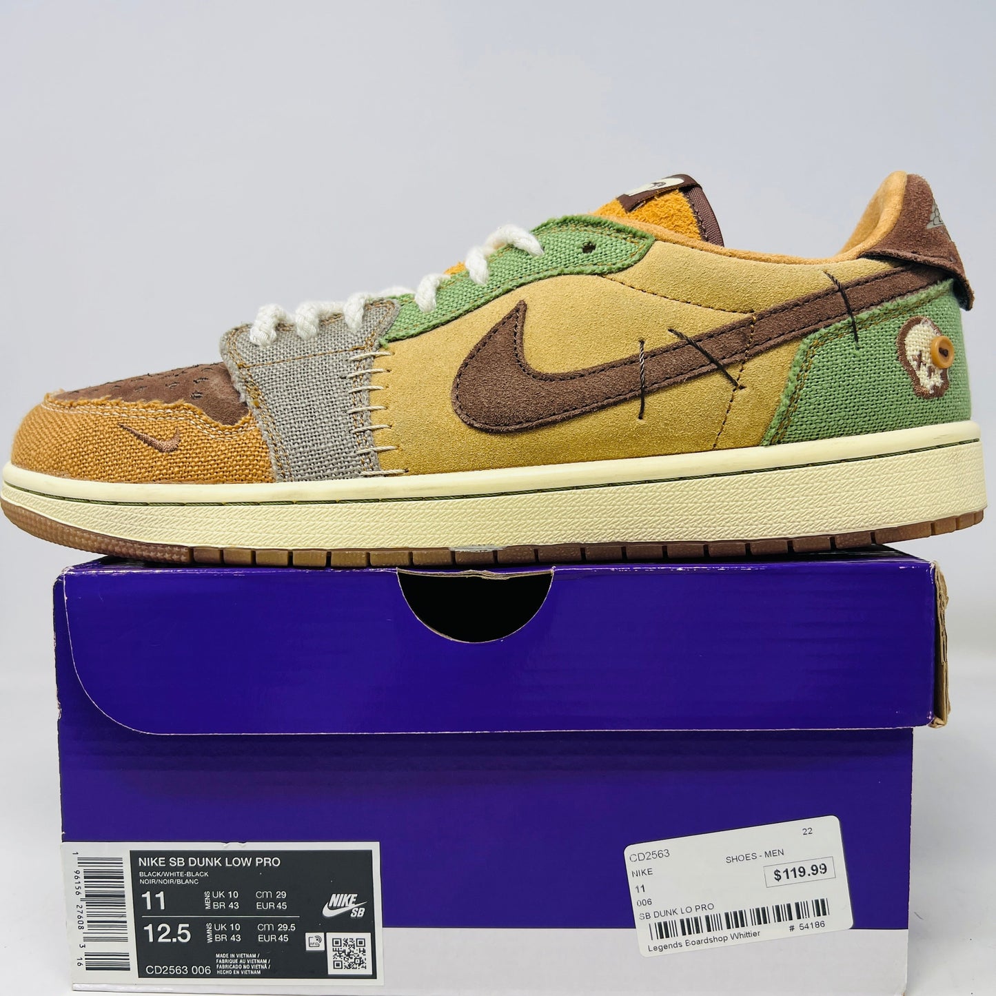 Multicolored Jordan 1 Retro Low OG Zion Williamson Voodoo sneakers feature a patchwork design and visible stitching with brown, yellow, and green sections. The stylish kicks have clean uppers with minimal heel drag, set elegantly on a purple box displaying size and price labels.