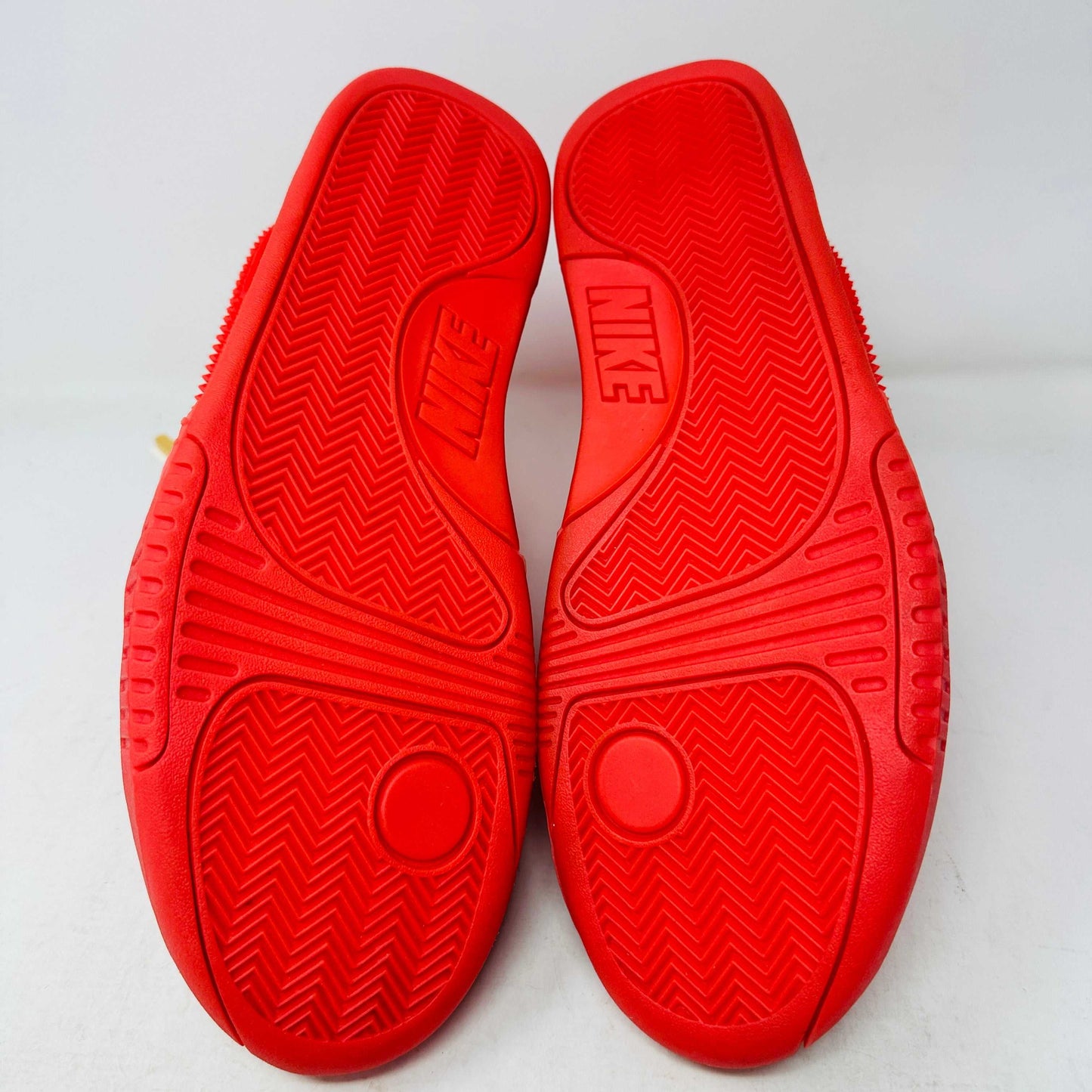 A pair of Nike Air Yeezy 2 Red October high-top sneakers, 100% authentic and brand new, features laces, a midfoot strap, and textured side detailing. Seen from the front against a white background, these bright red shoes showcase their unique style.
