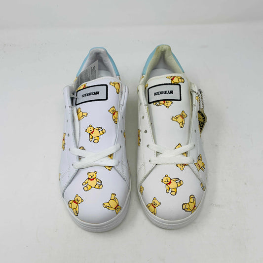 The Wmns Flavor Ice Cream Low Teddy Bears by ice cream are white sneakers adorned with a playful teddy bear pattern. They feature white laces and a small black and white label on the tongue, offering a whimsical and colorful design.