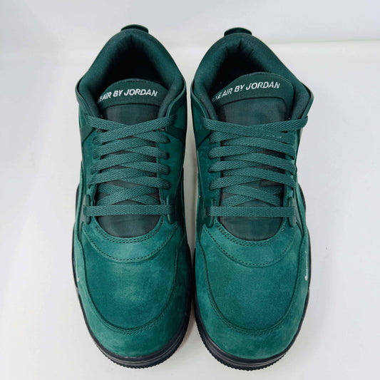 The Jordan 4 RM SP Nigel Sylvester Grandmas Driveway sneakers feature a dark green color with Air by Jordan on the tongue in white, accented with white laces and a low-top design, all set against a plain white background.