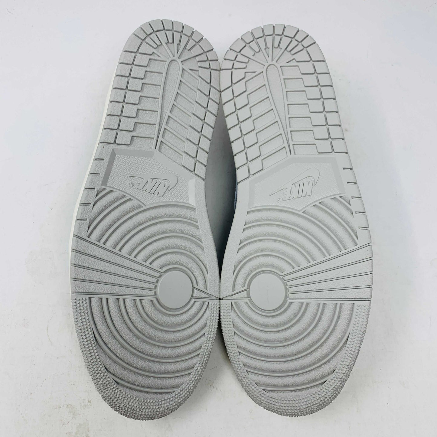 The Jordan 1 Retro Low OG Black Cement sneaker, with black and gray elephant print and a white swoosh, is showcased on a matching shoe box. A small brown box with extra laces is beside it, all set against a plain background.