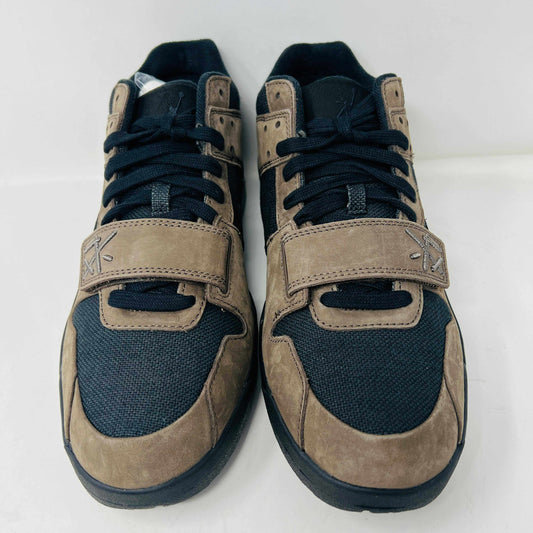 A pair of Jordan Jumpman Jack TR Travis Scott Dark Mocha sneakers are showcased on a brown box labeled JACK in white. The brown and black sneaker features a black swoosh, laces, and textured sole. Its 100% authentic with extra laces and bag, set against a plain white background.