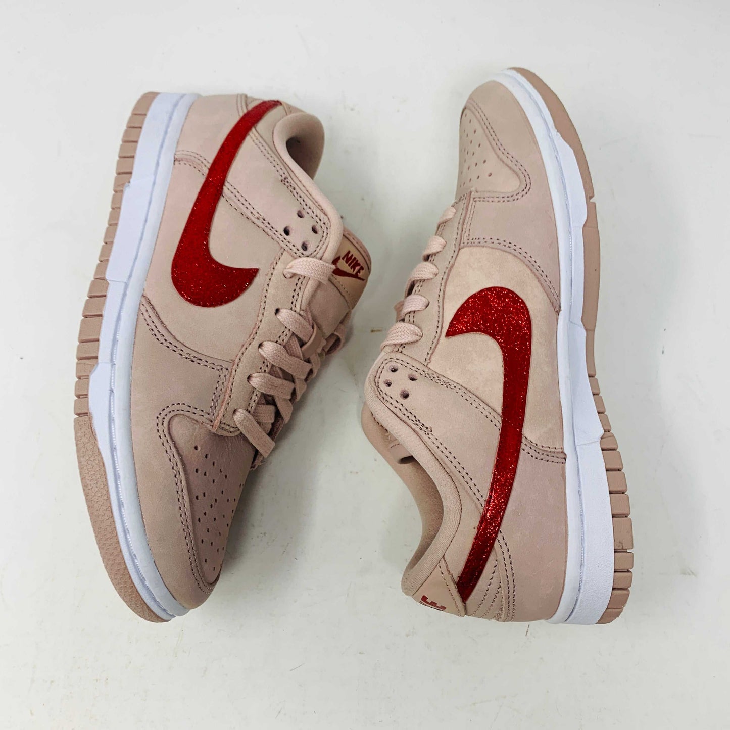 The Nike Dunk Low PRM Pink Oxford (W) Valentines Day CUSTOM features a pair of beige sneakers with red glitter swooshes, white midsoles, beige laces, and gum-colored outsoles, set side by side on a white background.