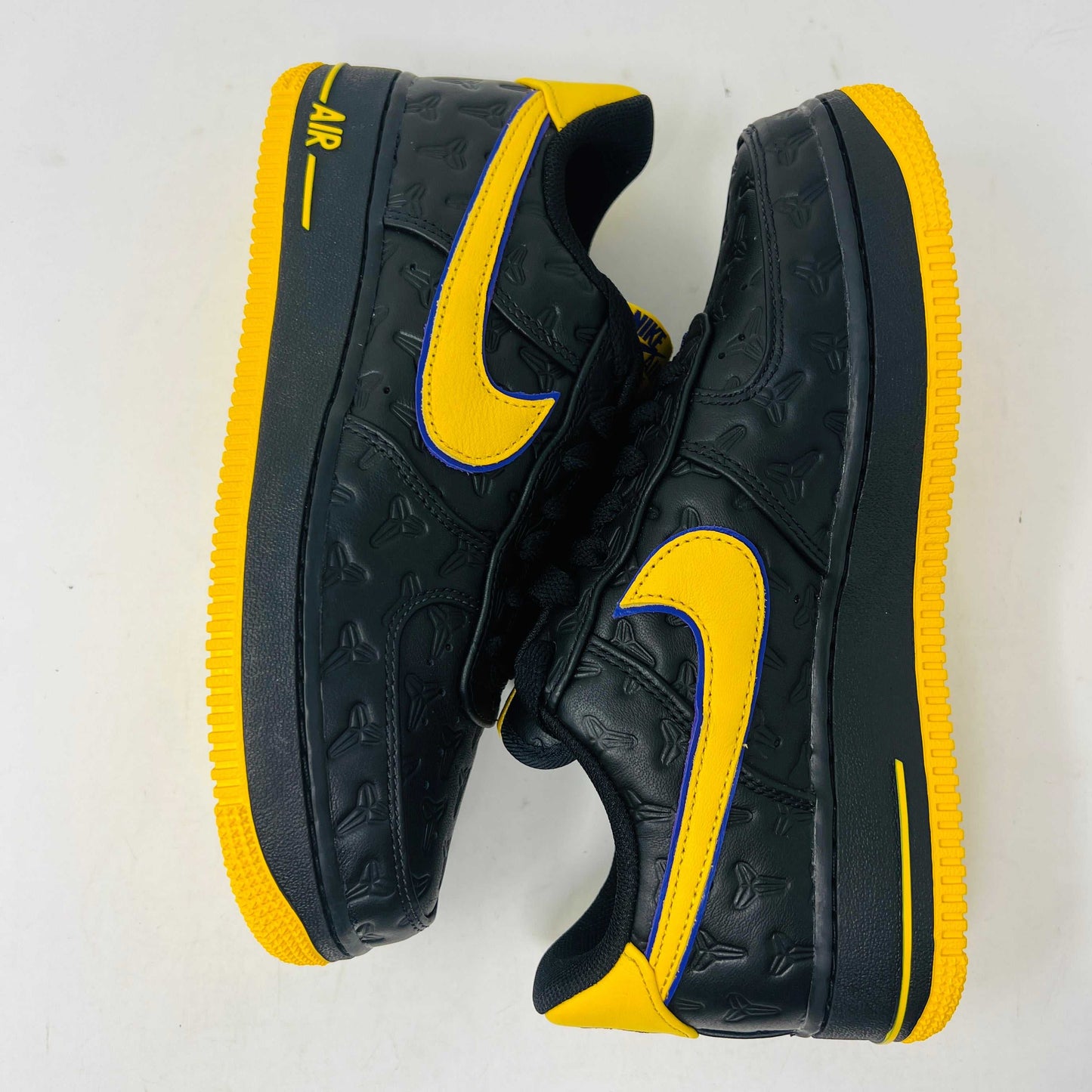 The new black Nike Air Force 1 Low Kobe Bryant Lakers Away sneakers have yellow accents like a swoosh and sole, sitting on a white box with the Nike logo and icon. These 100% authentic shoes are available as a final sale item.