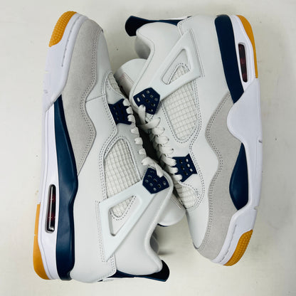 The Jordan 4 Retro SB Navy from Holy Ground Sneaker Shop, with white and navy mesh and orange details, sits on a pristine box showcasing the Nike SB logo. Its cushioned heel ensures its a perfect accessory addition.