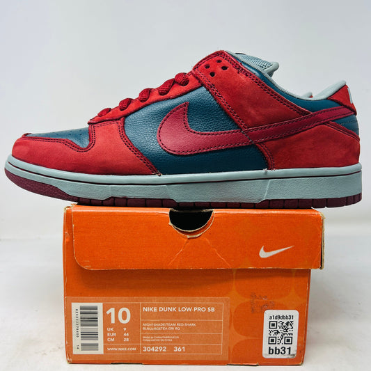 The Nike SB Dunk Low Shark sneaker, in red and grey, sits atop its vibrant orange box. The size 10 label is visible, indicating its well-preserved for sneaker enthusiasts.