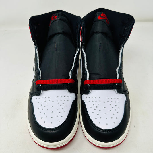 The Jordan 1 Retro High OG Black Toe Reimagined sits atop its box, featuring a black, white, and red design with a Nike swoosh and Air Jordan on the side. Sold by Holy Ground Sneaker Shop, it includes extra laces and a box lid with detailed product information and bold side designs.