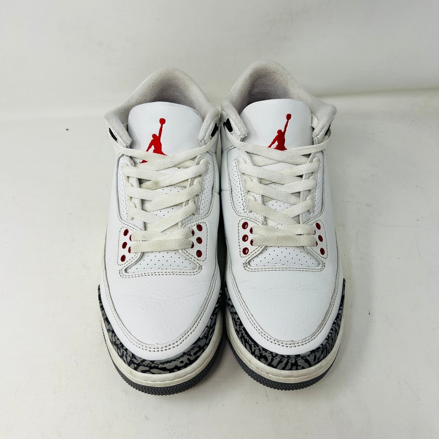 The Jordan 3 Retro White Cement Reimagined sneakers by Jordan feature a clean white upper with red accents, gray and black patterned trim on the toe and heel, white laces, and a red logo on the tongue, displayed upright on a pristine white background—perfect for everyday wear.