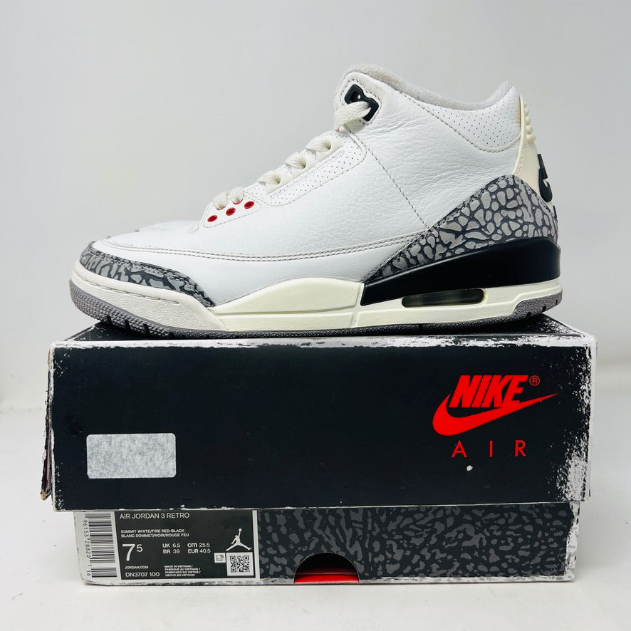 A Jordan 3 Retro White Cement Reimagined sneaker by Jordan, featuring a clean white and gray upper with a black and red sole, rests on its original box. The box is in excellent condition, displaying a black design with a red Nike Air logo and iconic gray elephant print on the lower half.
