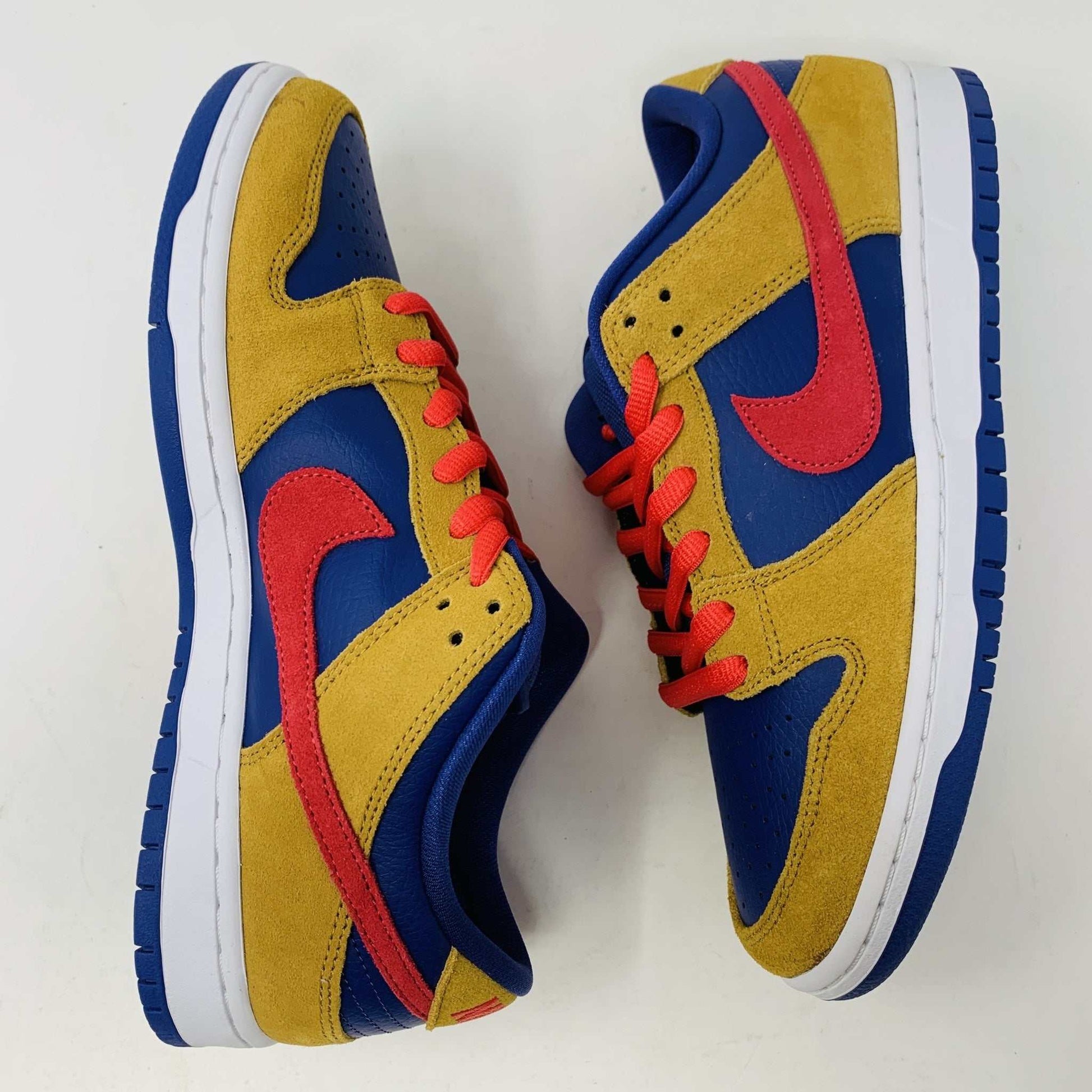 The Nike SB Dunk Low Reverse Papa Bear features a blue and yellow suede upper, a red Swoosh, and orange laces. It comes with extra yellow laces in front of its purple Nike SB box and is 100% authentic.
