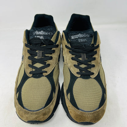 The New Balance 990v3 MiUSA JJJJound Brown Black athletic shoe, released in 2022, features tan and black mesh-suede uppers with an N logo on the side and 990 on the heel. It sits atop a black shoebox with the label M990JJ3 and shows light wear.
