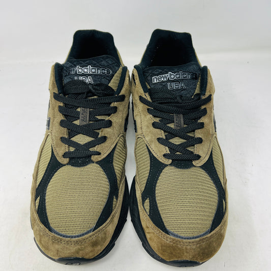 The New Balance 990v3 MiUSA JJJJound Brown Black athletic shoe, released in 2022, features tan and black mesh-suede uppers with an N logo on the side and 990 on the heel. It sits atop a black shoebox with the label M990JJ3 and shows light wear.