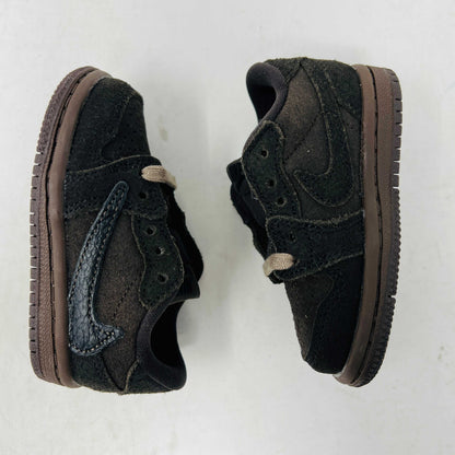 A Jordan 1 Retro Low OG SP Travis Scott Velvet Brown (TD) sneaker with a unique swoosh design sits on a white shoebox. It includes extra pink and black laces, is 100% authentic, brand new, and ready to elevate your style with its sleek look.