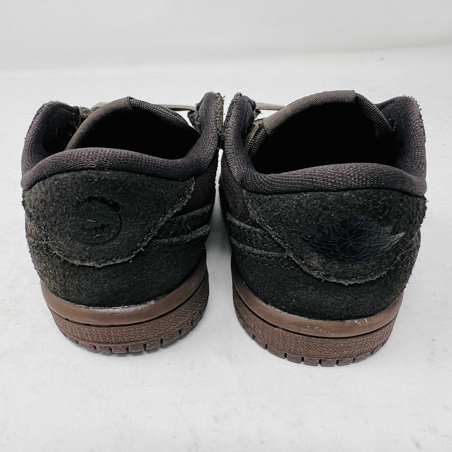 A Jordan 1 Retro Low OG SP Travis Scott Velvet Brown (TD) sneaker with a unique swoosh design sits on a white shoebox. It includes extra pink and black laces, is 100% authentic, brand new, and ready to elevate your style with its sleek look.