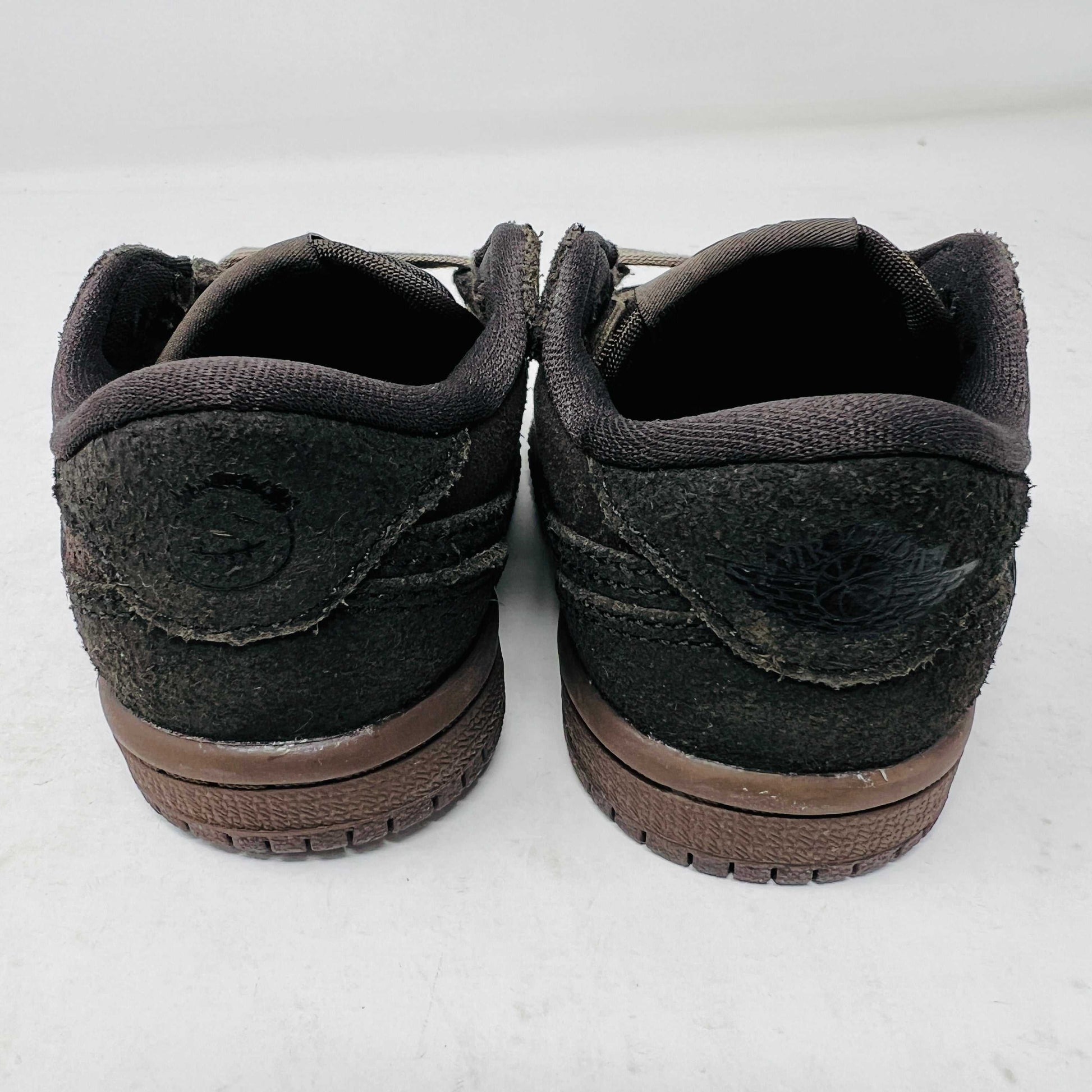 A Jordan 1 Retro Low OG SP Travis Scott Velvet Brown (TD) sneaker with a unique swoosh design sits on a white shoebox. It includes extra pink and black laces, is 100% authentic, brand new, and ready to elevate your style with its sleek look.