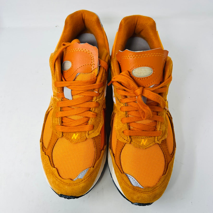 Brand new New Balance 2002R Protection Pack sneakers in Vintage Orange sit on their box, featuring a suede and mesh design, white N logo on sides, gray and white sole. Box in pristine condition with label for mens size 10.5, UK size 9.5.