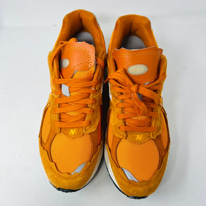 Brand new New Balance 2002R Protection Pack sneakers in Vintage Orange sit on their box, featuring a suede and mesh design, white N logo on sides, gray and white sole. Box in pristine condition with label for mens size 10.5, UK size 9.5.