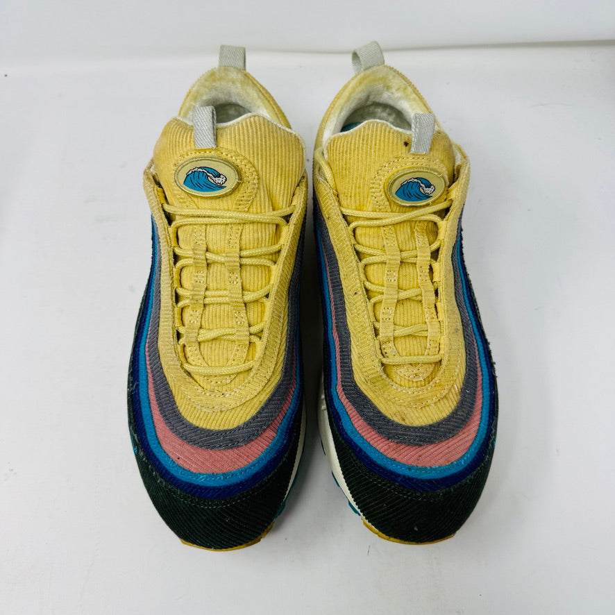 The Nike Air Max 1/97 Sean Wotherspoon sneaker, featuring a multicolored wave-like design, rests on a New Balance box and includes extra blue, white, and dark blue laces. It showcases an authentic air cushion in the sole.