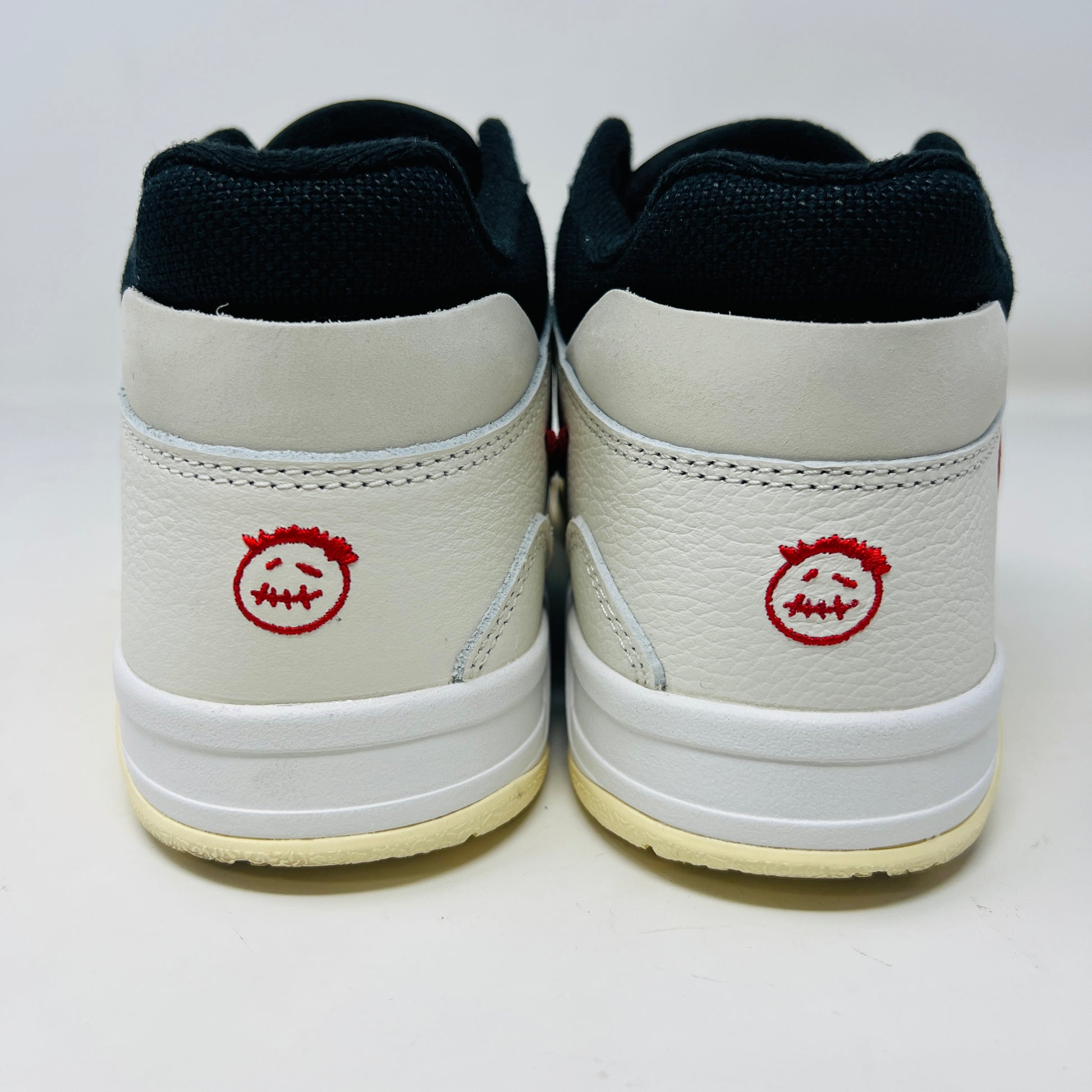 The Jordan Jumpman Jack TR Travis Scott University Red sneakers, black and white with red swooshes, rest on a brown shoe box. Three lace sets in red, cream, and black with white speckles are individually packaged in front. The box label displays sizes 9 and 10.5.