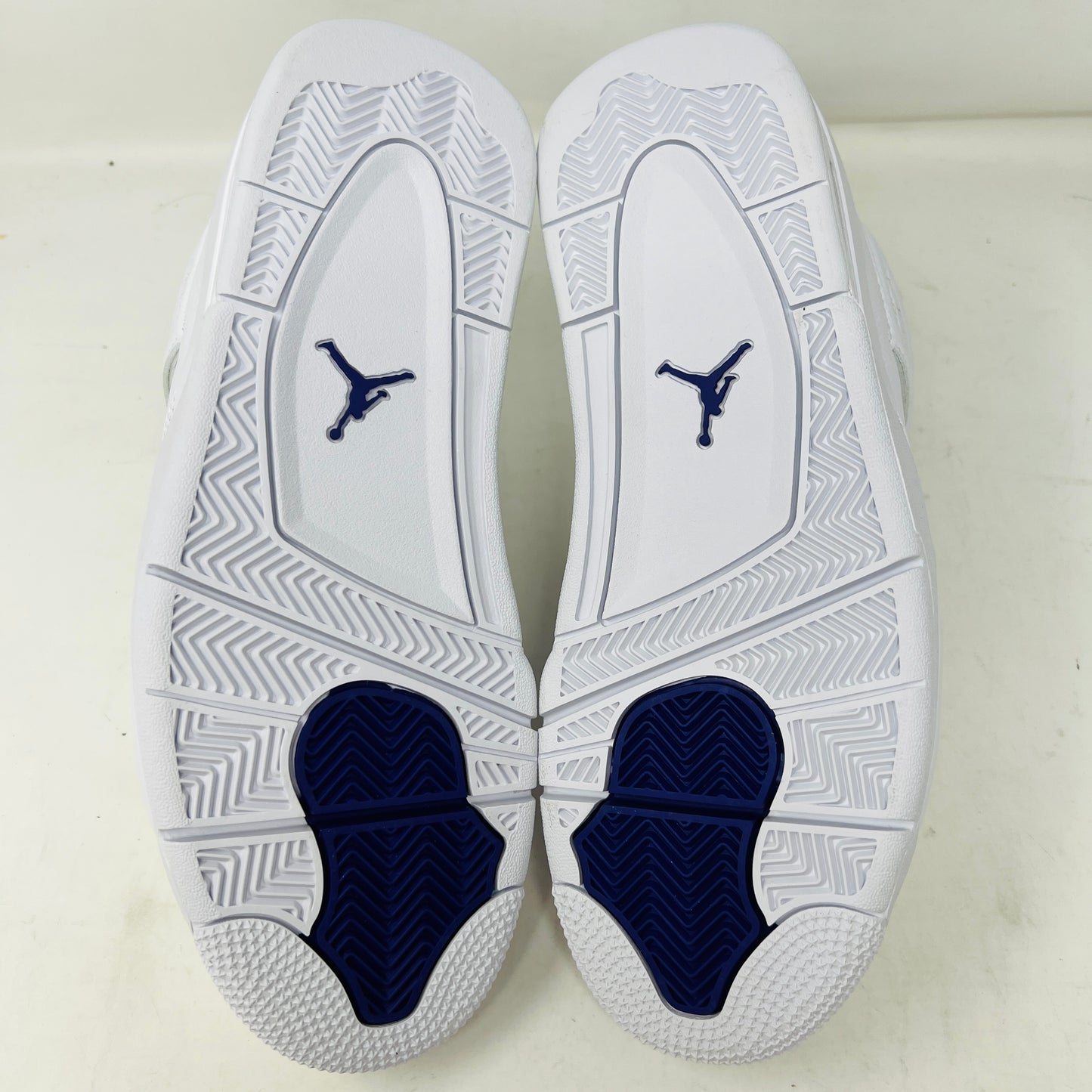 The Jordan 4 Retro Metallic Purple sneaker features white material with blue mesh accents, a visible air cushion in the heel, textured sole, angular overlays, and a padded collar. Note: no box included.