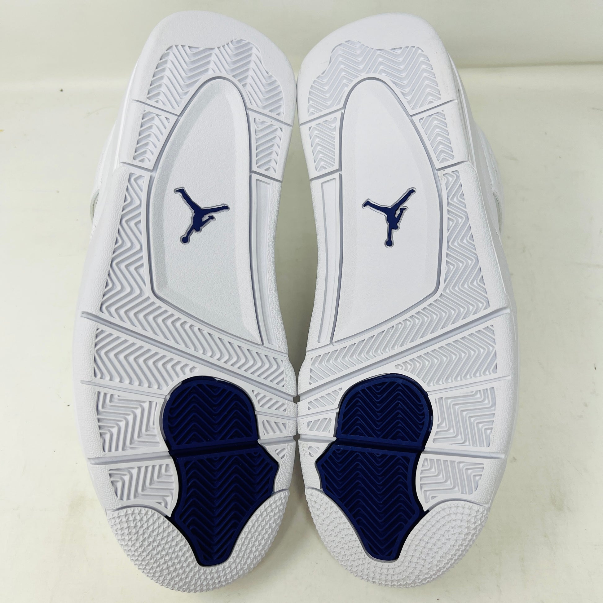 The Jordan 4 Retro Metallic Purple sneaker features white material with blue mesh accents, a visible air cushion in the heel, textured sole, angular overlays, and a padded collar. Note: no box included.