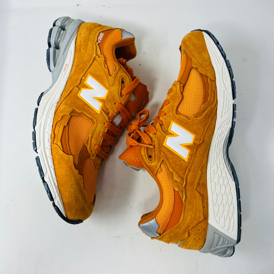 Brand new New Balance 2002R Protection Pack sneakers in Vintage Orange sit on their box, featuring a suede and mesh design, white N logo on sides, gray and white sole. Box in pristine condition with label for mens size 10.5, UK size 9.5.