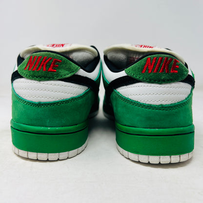 The Nike SB Dunk Low Heineken sneaker, featuring a green, white, and black design with red laces and a red star on the heel, sits on its box. A small package of green shoelaces is beside it. The box displays the size and Nike branding.