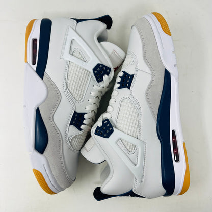 The Jordan 4 Retro SB Navy from Holy Ground Sneaker Shop, with white and navy mesh and orange details, sits on a pristine box showcasing the Nike SB logo. Its cushioned heel ensures its a perfect accessory addition.