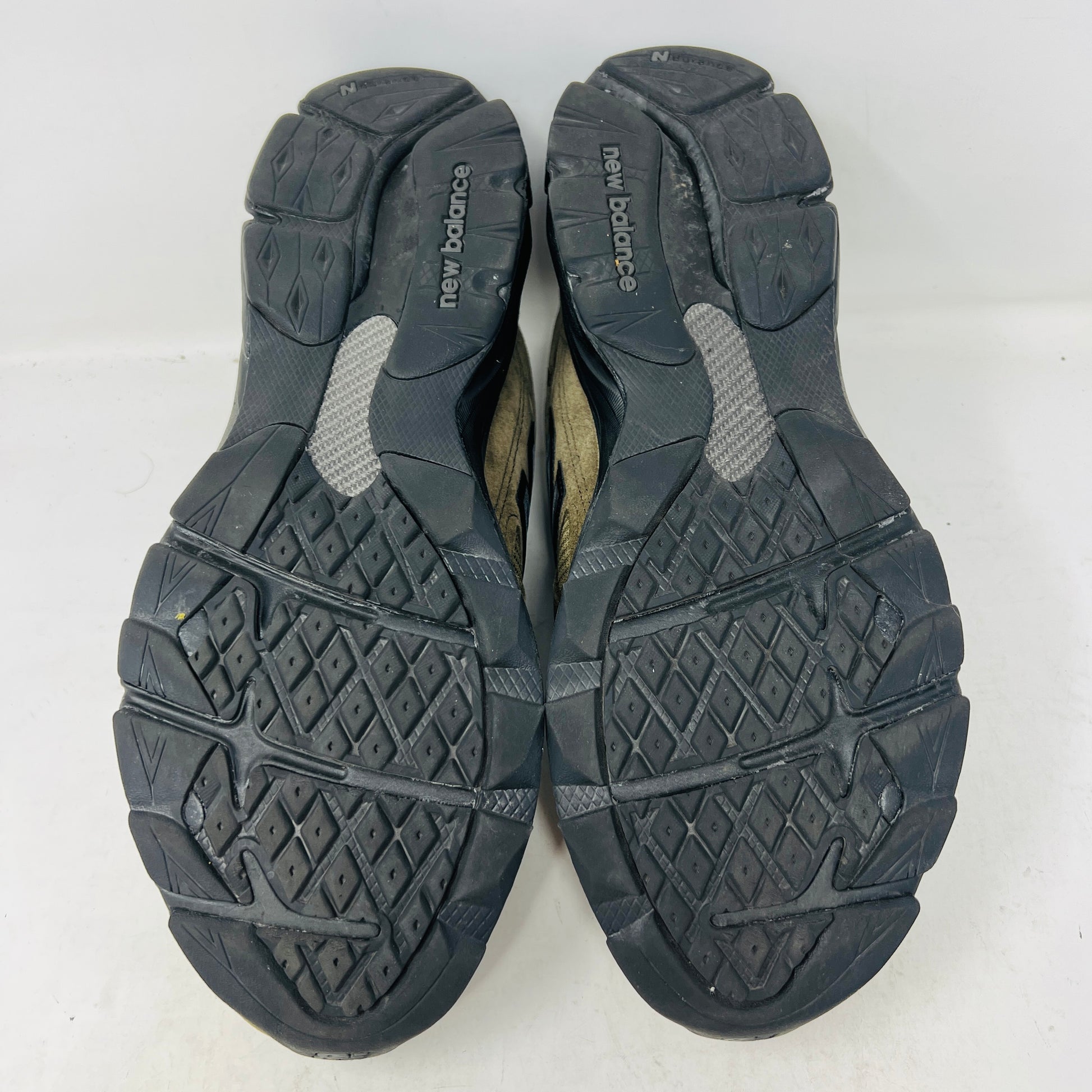 The New Balance 990v3 MiUSA JJJJound Brown Black athletic shoe, released in 2022, features tan and black mesh-suede uppers with an N logo on the side and 990 on the heel. It sits atop a black shoebox with the label M990JJ3 and shows light wear.