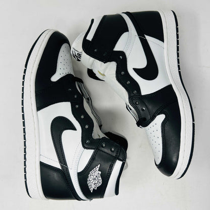 A Jordan 1 Retro High 85 Black White (2023) sneaker is showcased on a red Nike box. This black and white high-top features the Air Jordan logo and includes extra white laces.