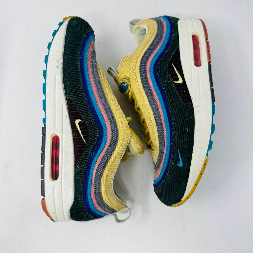 The Nike Air Max 1/97 Sean Wotherspoon sneaker, featuring a multicolored wave-like design, rests on a New Balance box and includes extra blue, white, and dark blue laces. It showcases an authentic air cushion in the sole.