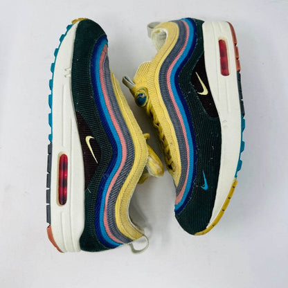 The Nike Air Max 1/97 Sean Wotherspoon sneaker, featuring a multicolored wave-like design, rests on a New Balance box and includes extra blue, white, and dark blue laces. It showcases an authentic air cushion in the sole.