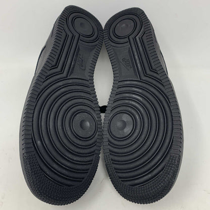 The Nike Supreme Air Force 1 Black features a perforated design on the toe box, black supreme laces with a shiny tag, and a prominent Nike logo, all set against a plain white background.