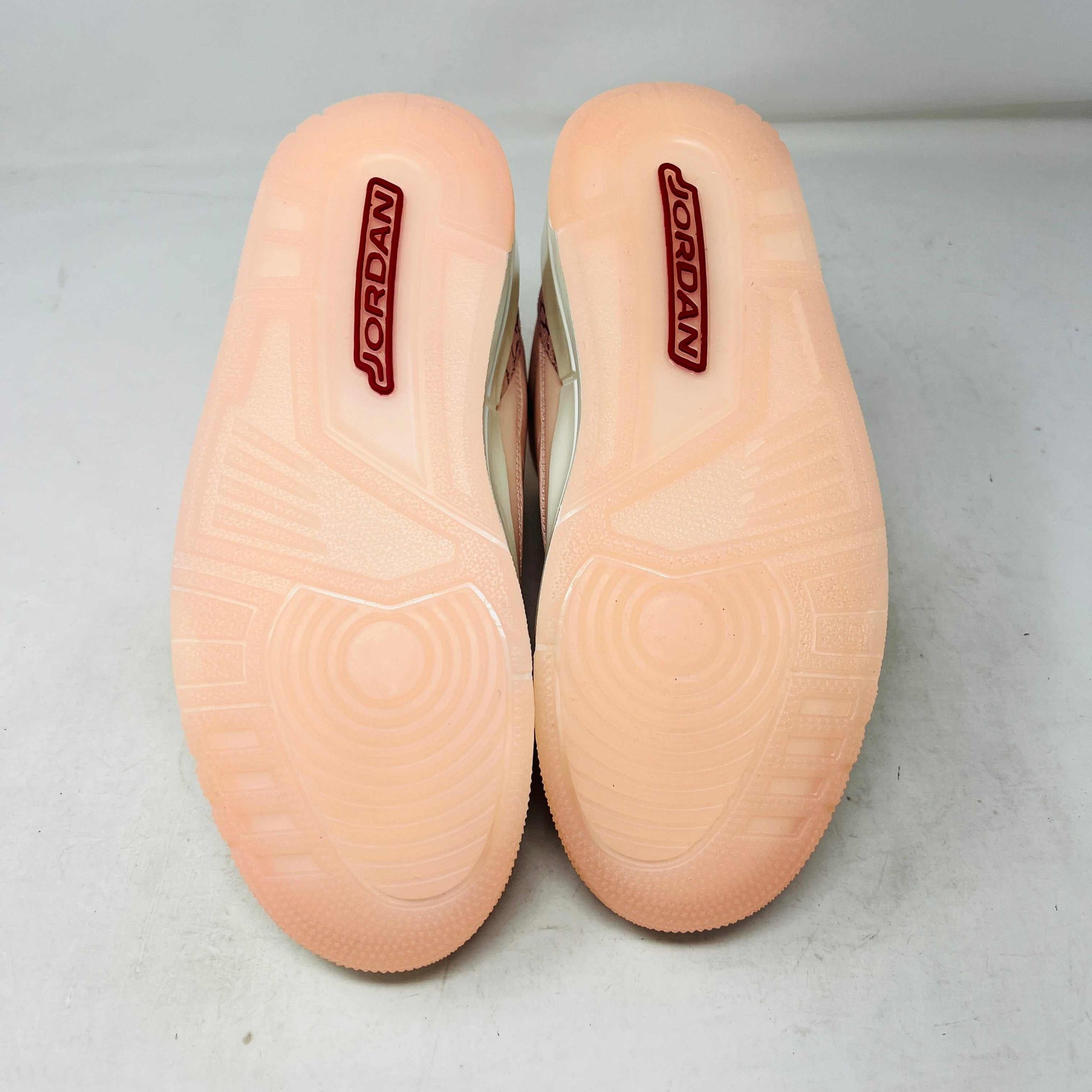 The BRAND NEW Jordan 3 Retro Valentines Day Treat Yourself (2025) (Womens) by Jordan, in pink and cream with textured heel and toe patterns, sits on a closed red shoebox. It features a translucent sole, red eyelets, and an authentic pendant on the laces sparkling like GEMS.