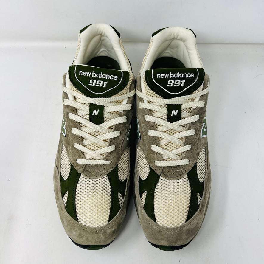 A pair of Holy Grounds New Balance 991 Aime Leon Dore MiUK Grey sneakers in gray, green, and beige are displayed on their shoebox. Comes with extra green and gray laces. The 2022 box details the size and model.