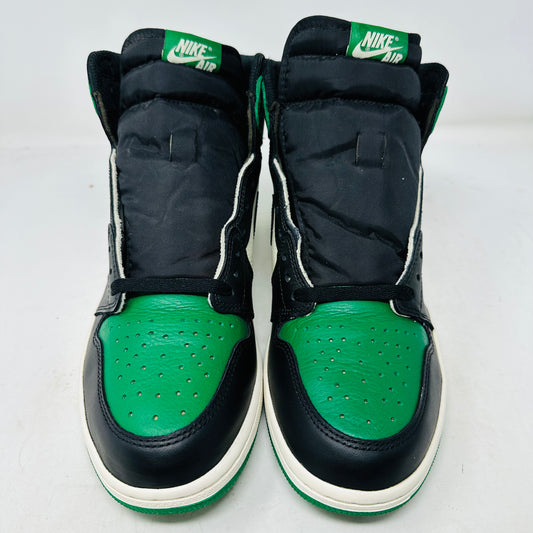 A pair of black, green, and white Jordan 1 Retro High Pine Green sneakers rests on a sleek black Nike shoebox. Featuring a prominent black swoosh and extra green laces, they have a faint smoke smell. The box lists size: USA 11, Euro 45, UK 10, CM 29.
